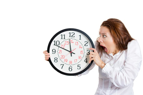 A closeup portrait of a business woman, executive, leader holding, looking anxiously at a clock, pressured by lack of time, running out, isolated on a white background with copy space. Human emotions